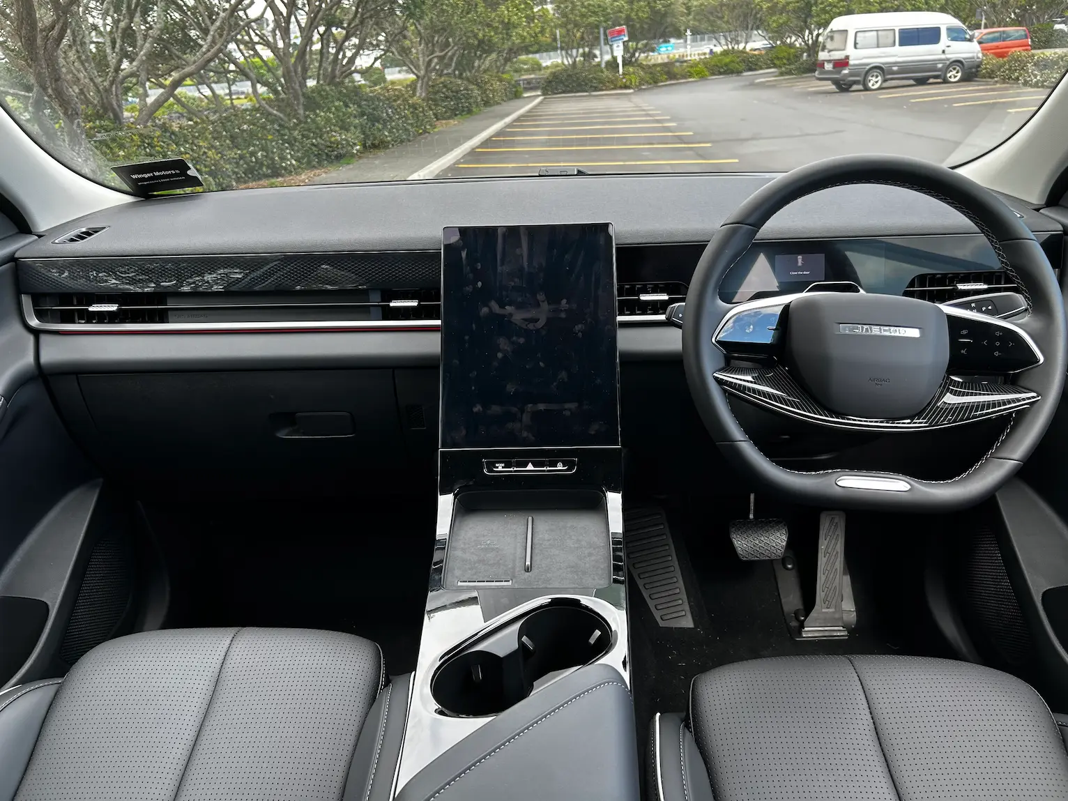 Interior view of a right-hand-drive JAECOO J5 SUV, showing the dashboard, steering wheel, large central touchscreen, and centre console.