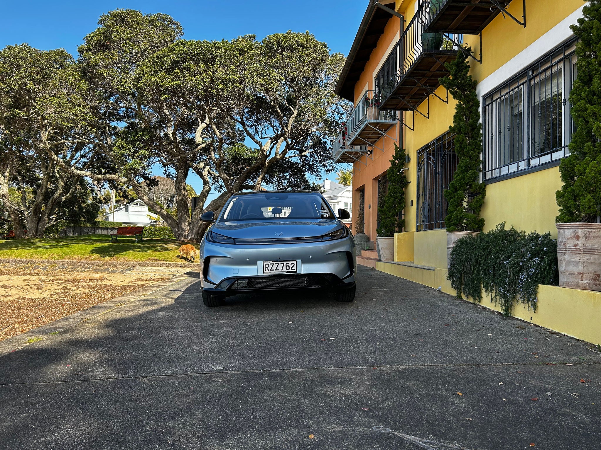 Front view of a light blue Arcfox T1 electric SUV parked next to colourful buildings and large trees.