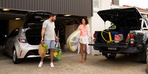 A couple taking groceries out of an open car trunk