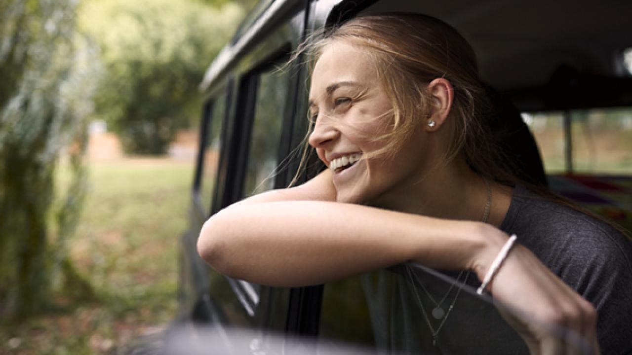 Girl with her head out the car window smiling