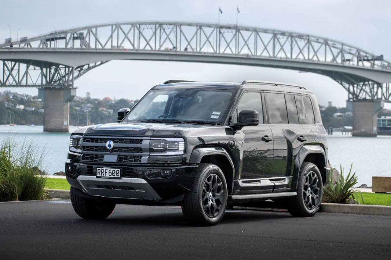 front quarter view of black SUV in front of harbour