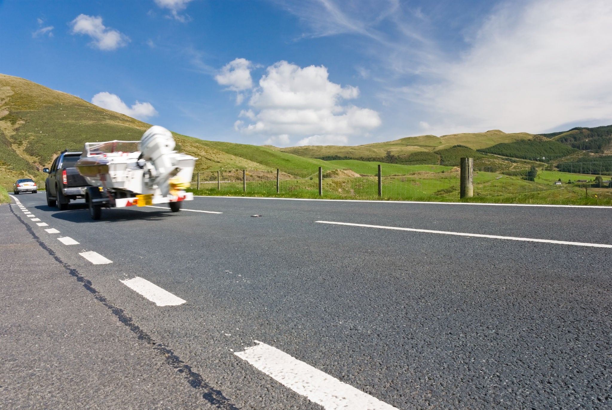 Car towing motor boat on a mountain road in Wales, UK.