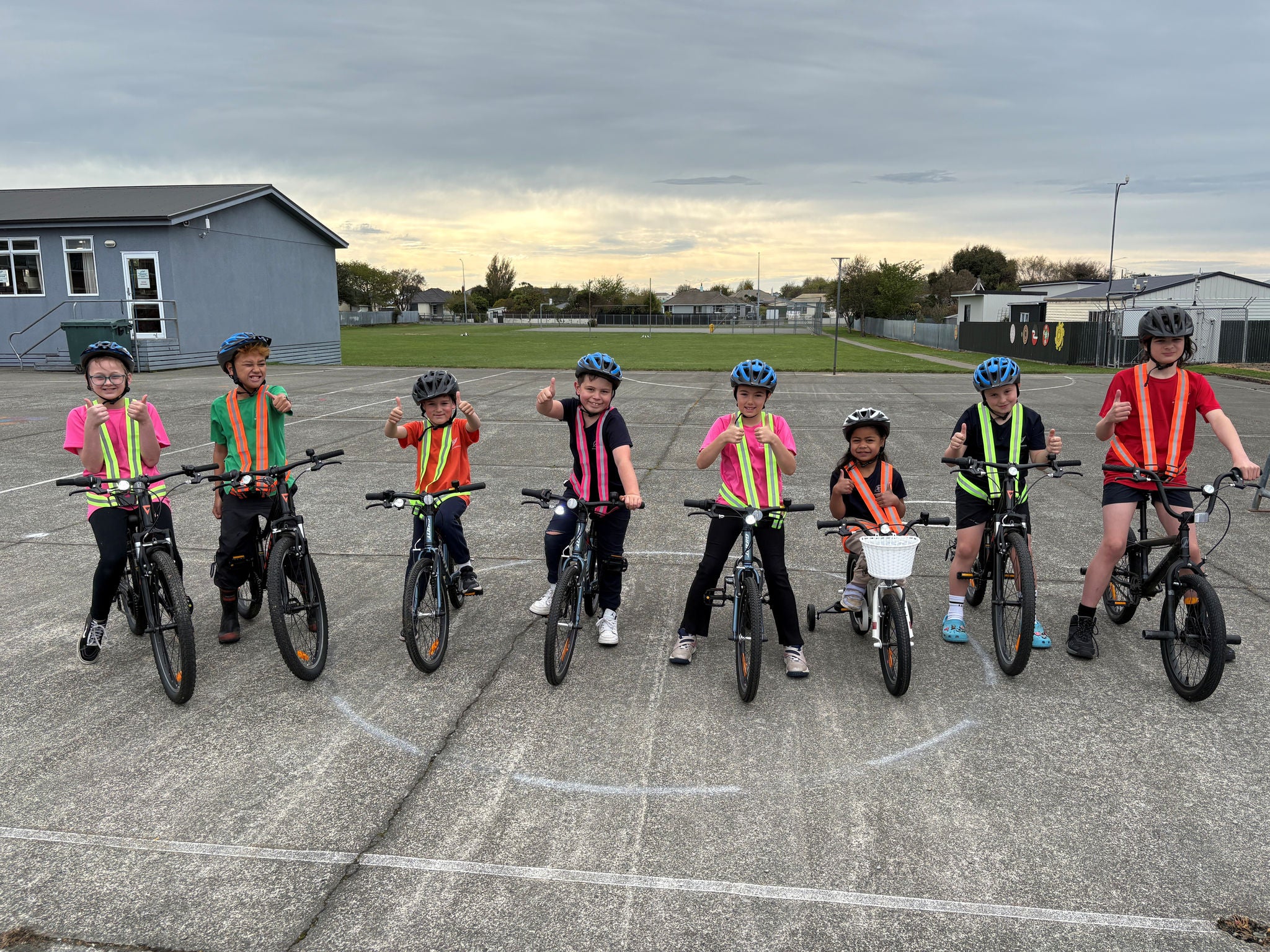 A line of children sitting on their bikes with bike lights and hi-vis straps on