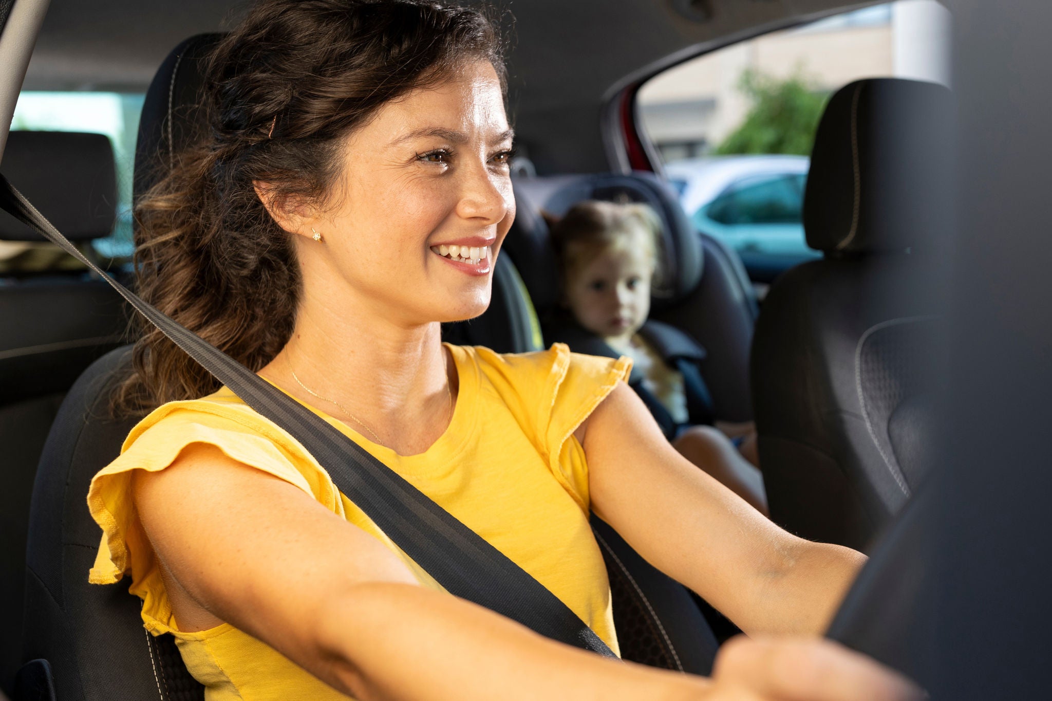 Mother driving while child is safely seated in car seat