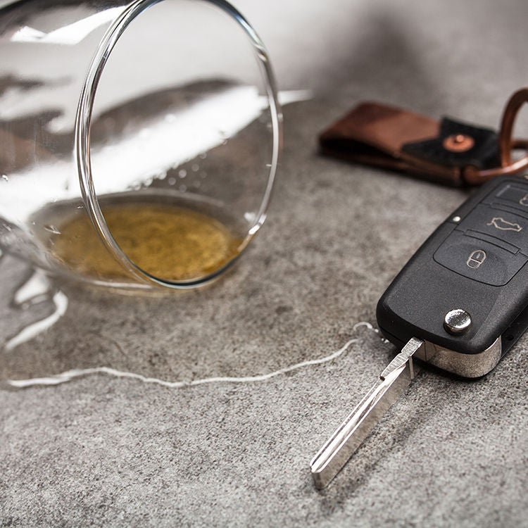 A beer glass spilling liquid next to a pair of car keys