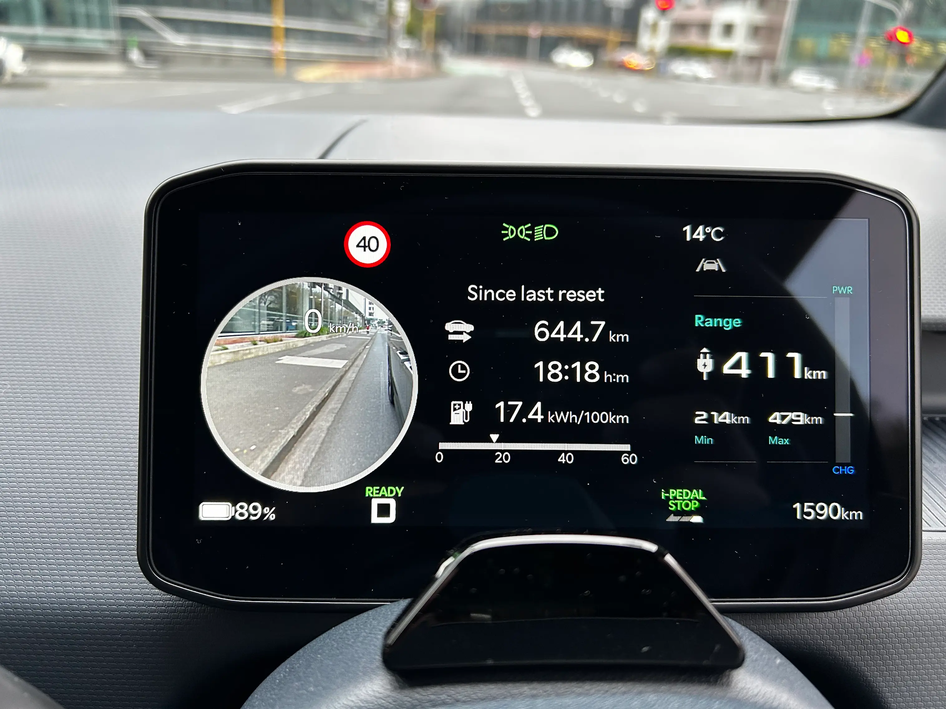 Digital driver display inside a Kia PV5 electric van showing an estimated driving range of 411km and battery charge of 89% while parked in an urban area.