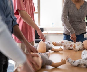 Adults performing CPR on a baby mannequin