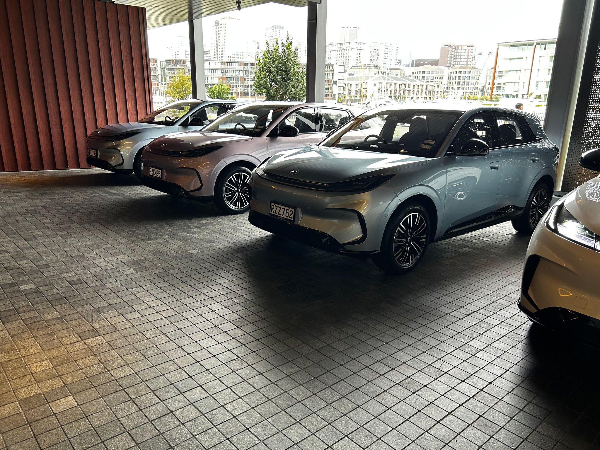Three Arcfox T1 electric SUVs lined up in a covered display area overlooking a cityscape.