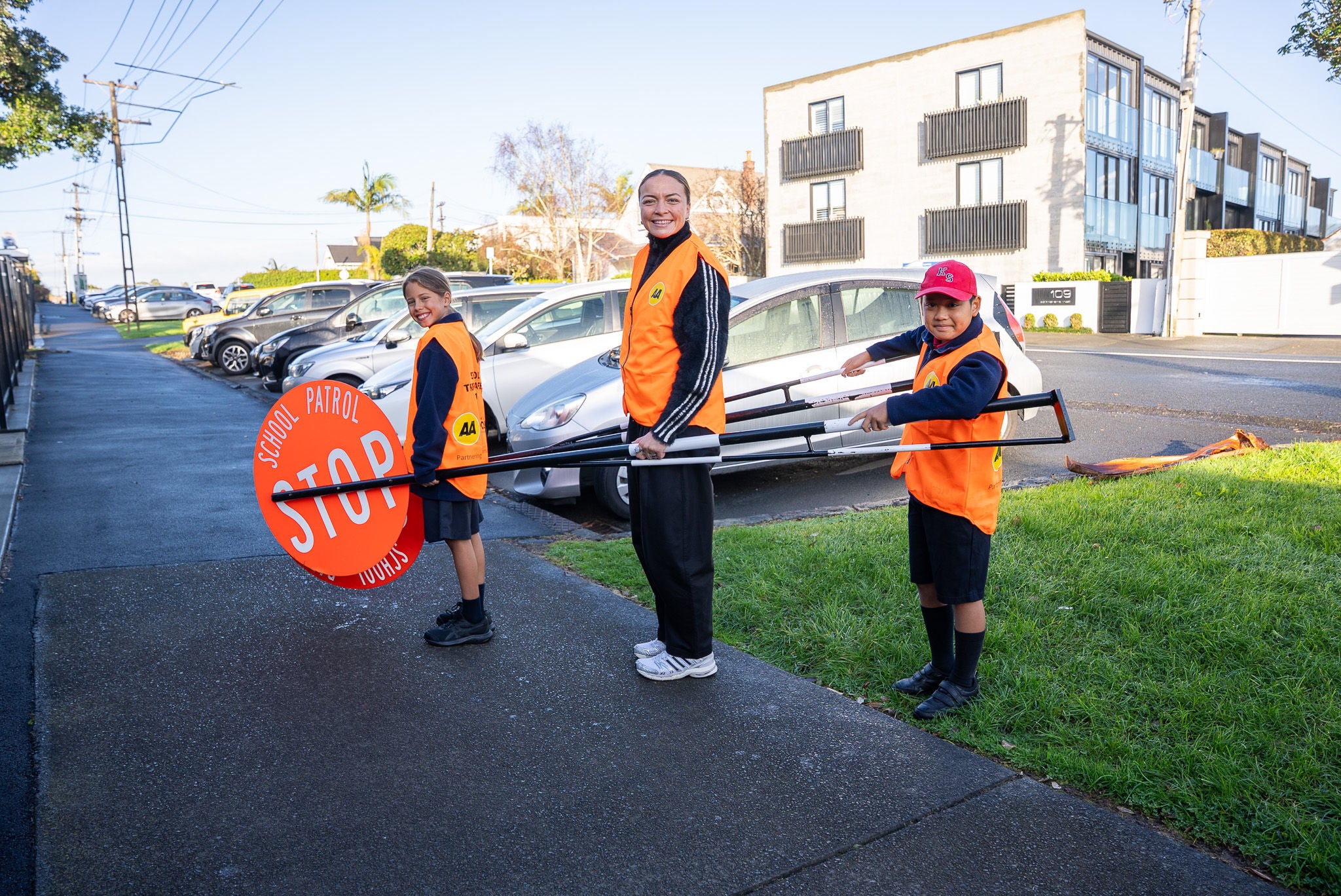 Image of Renee Holmes with two primary school students holding the 'lollipop' signs