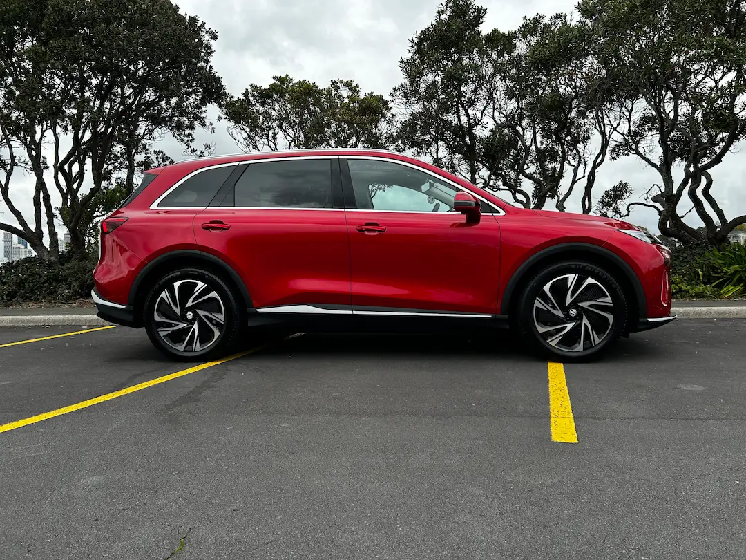 Side view of a red MG electric SUV parked in a car park.