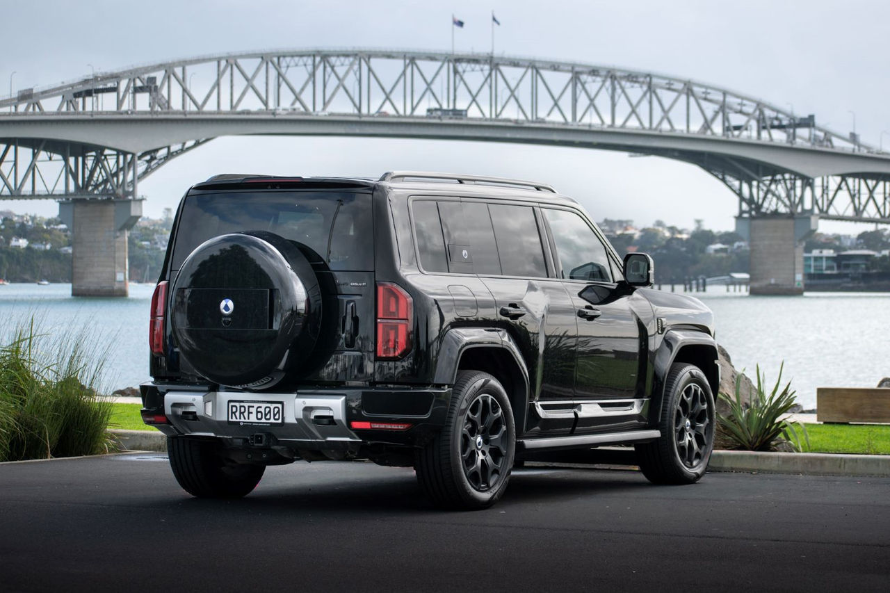 rear quarter view of black SUV in front of harbour