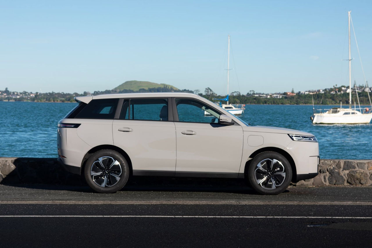 side on view of grey SUV in front of water