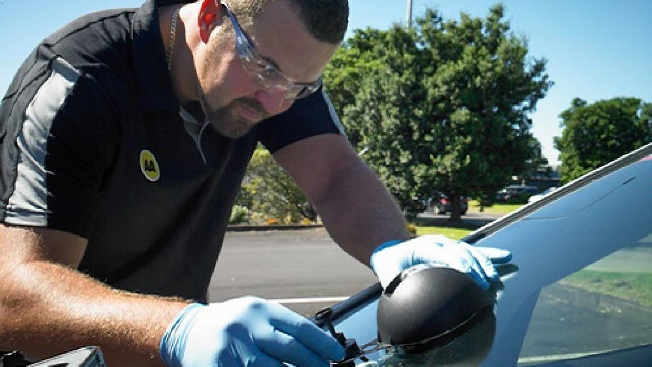 AA repairer fixing chip on car window