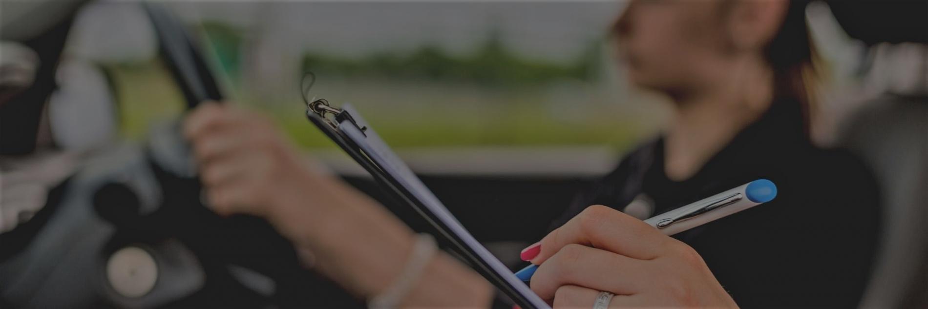 Close up image of a hand of an AA driving instructor writing