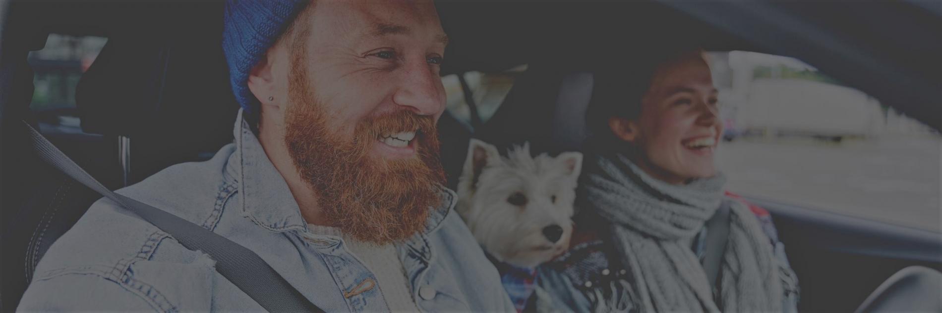 A man and woman smiling in the front seat of a car