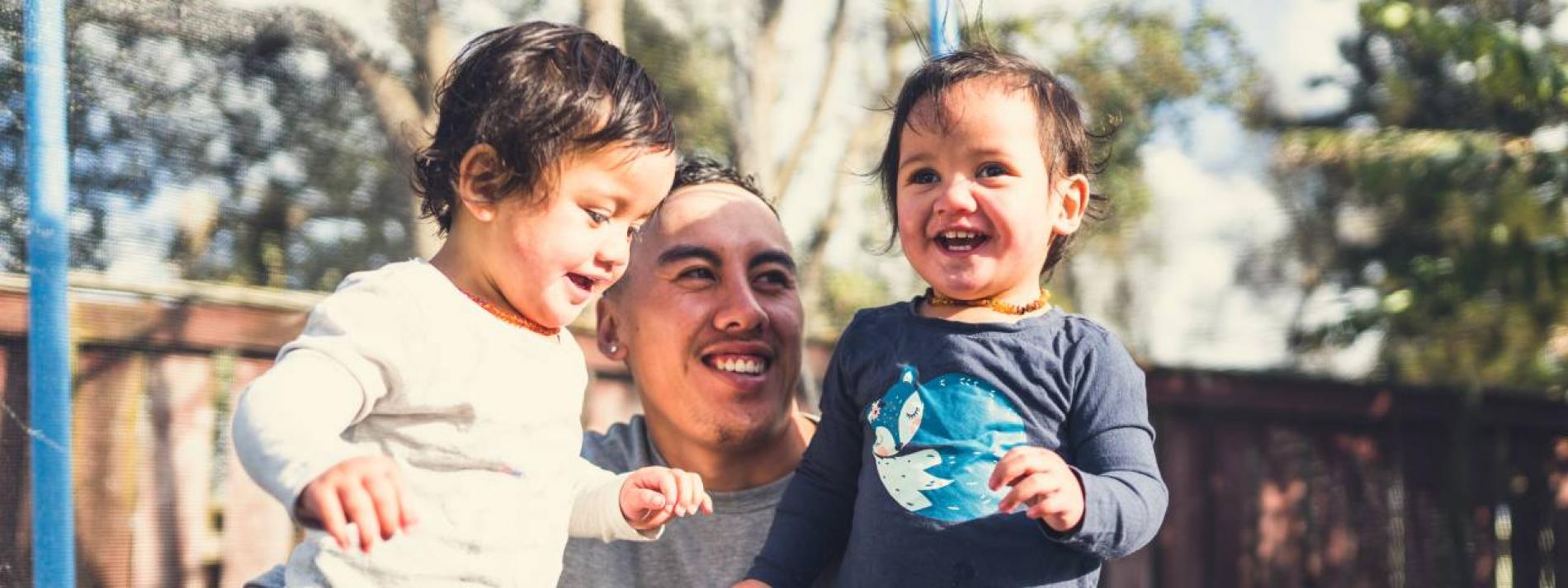 A father and his two young children laughing together.
