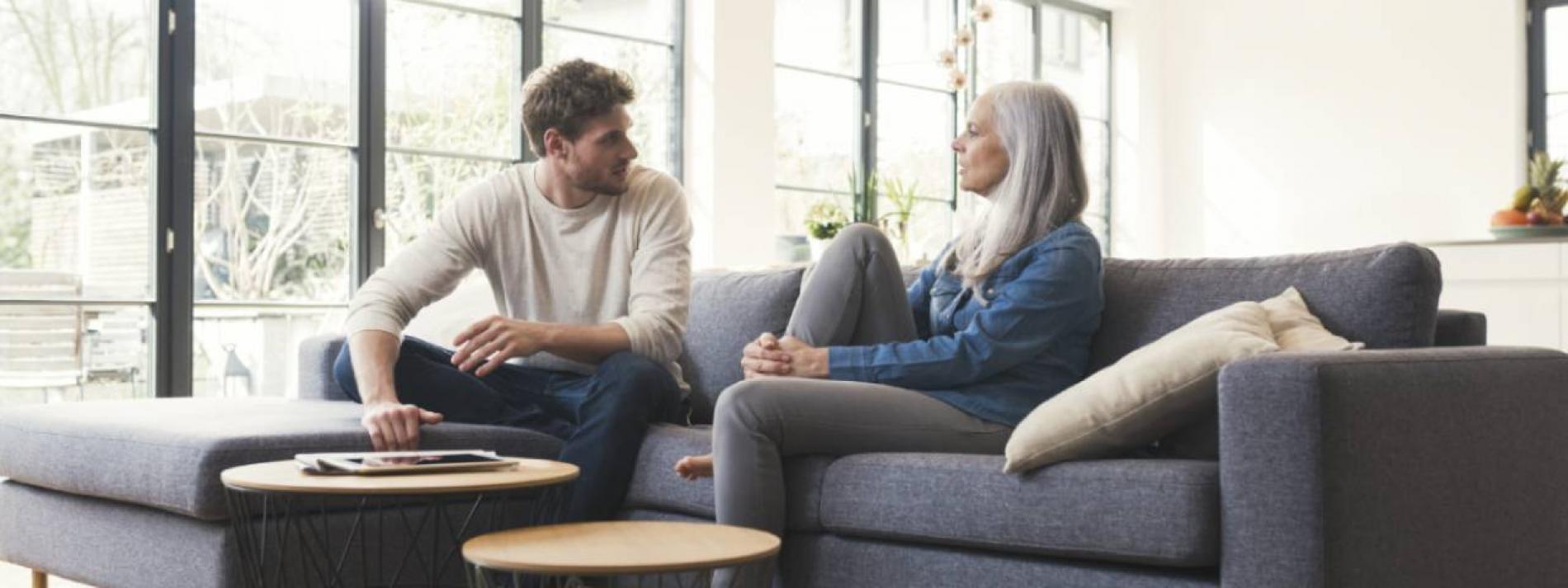 A woman and a man talking to each other while sitting on a couch