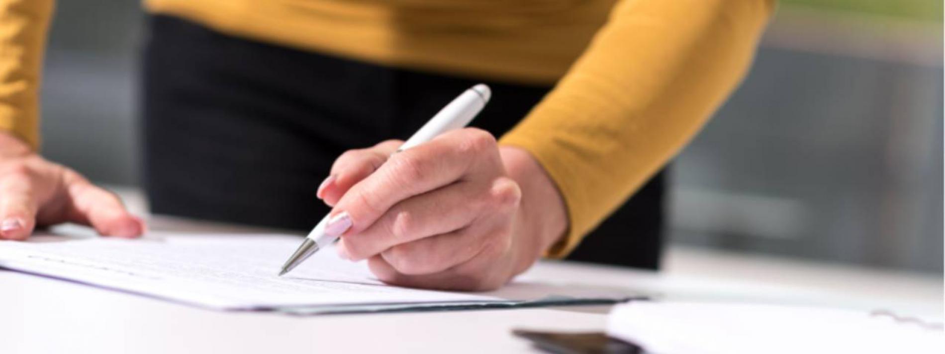 A hand holding a pen writing on a paper