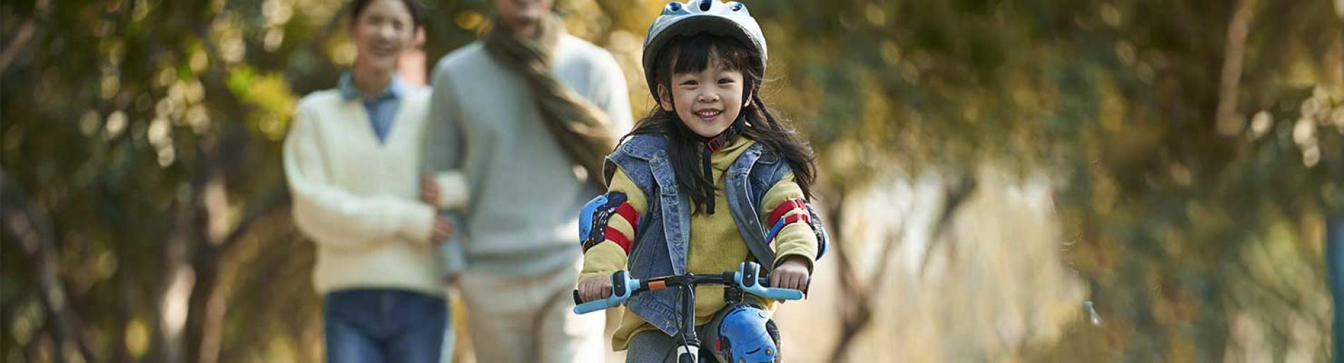 Parents watching their daughter riding a bike
