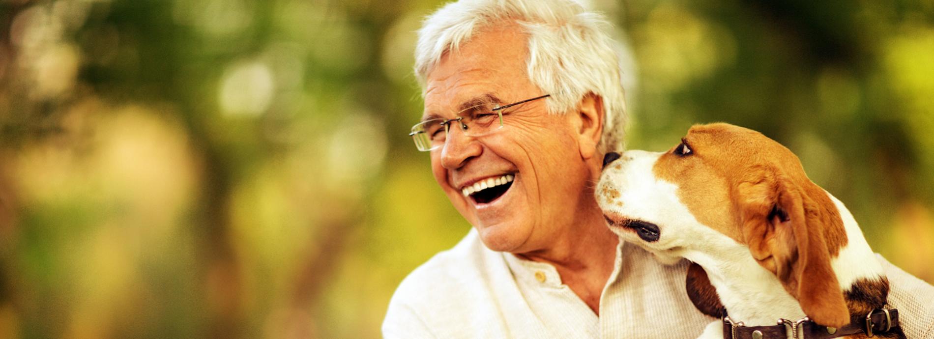 An old man laughing while holding his dog