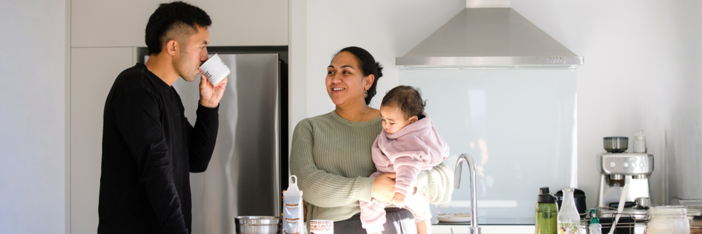 Two young parents with a baby standing in a modern kitchen