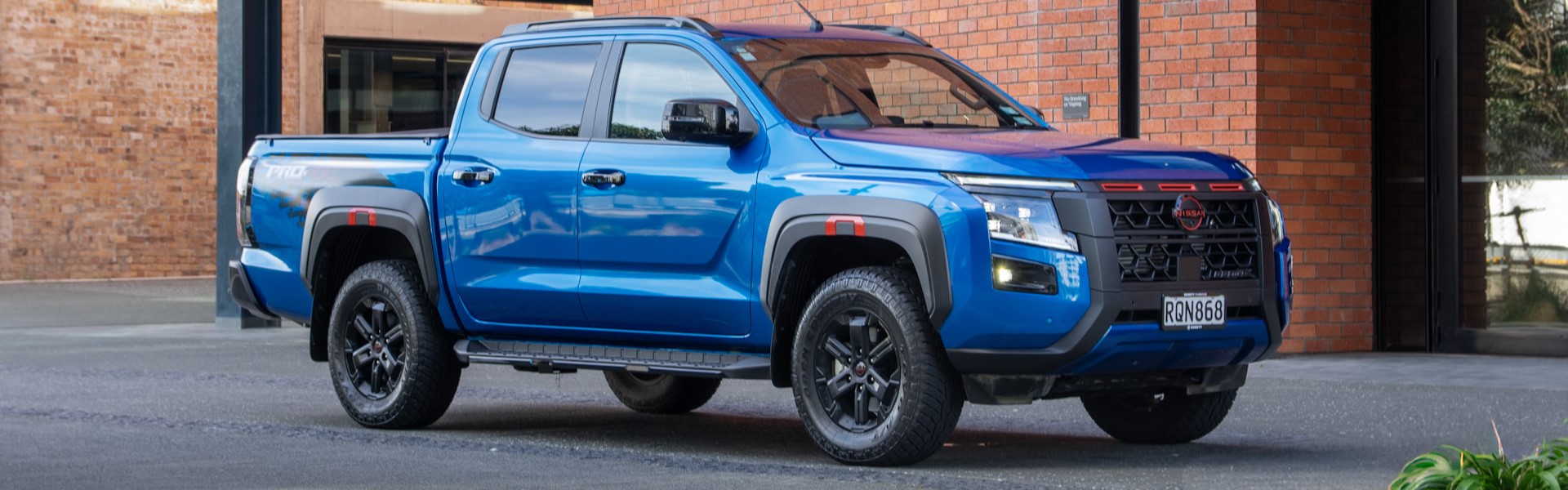 Blue ute in front of red brick building
