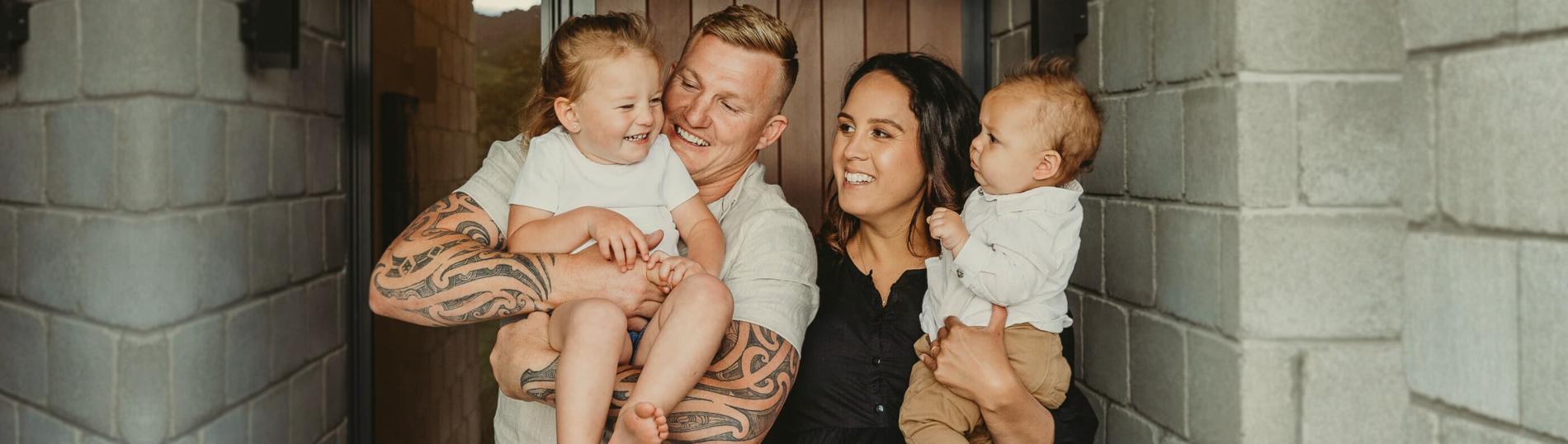 Young family smiling together outside their home