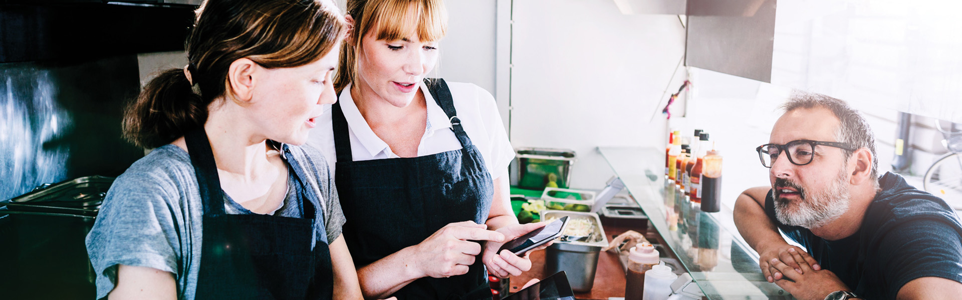 Two women staff in a cafe serving a customer