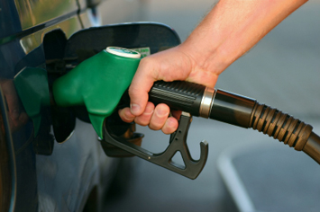 A hand holding a fuel pump up to a car to refuel it.