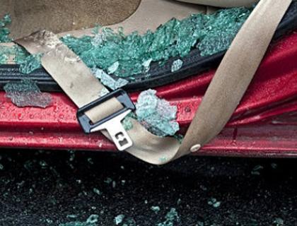 An upside down car door with shattered glass everywhere,  there is a seatbelt across it.