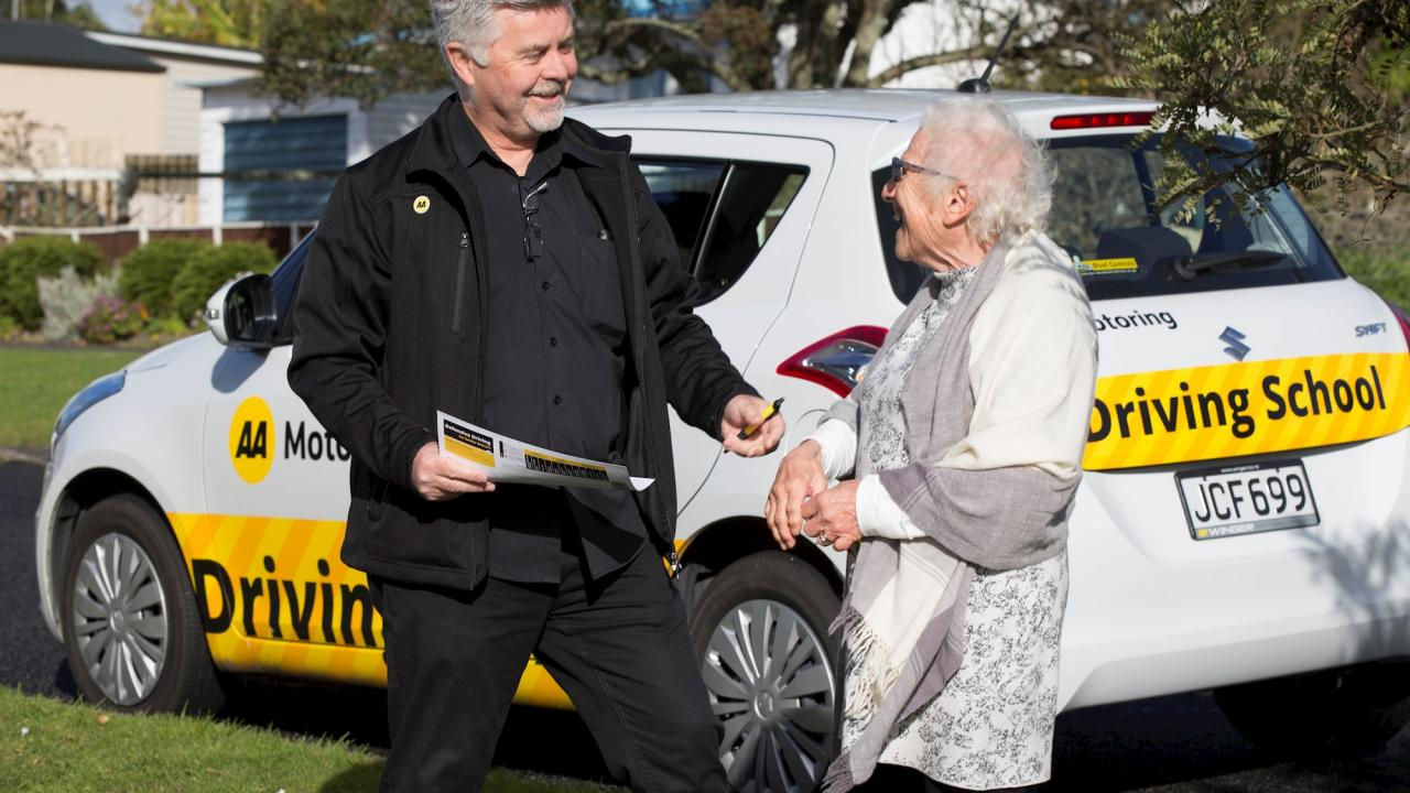 An AA Driving instructor laughing with an elderly woman