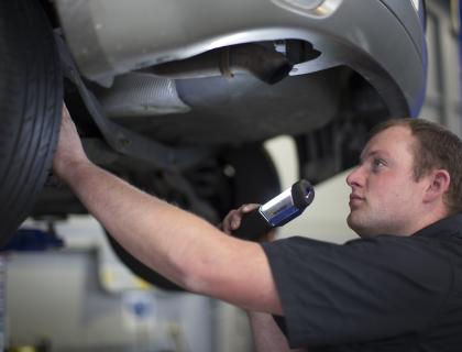 Man checking tire in Warrant of Fitness check