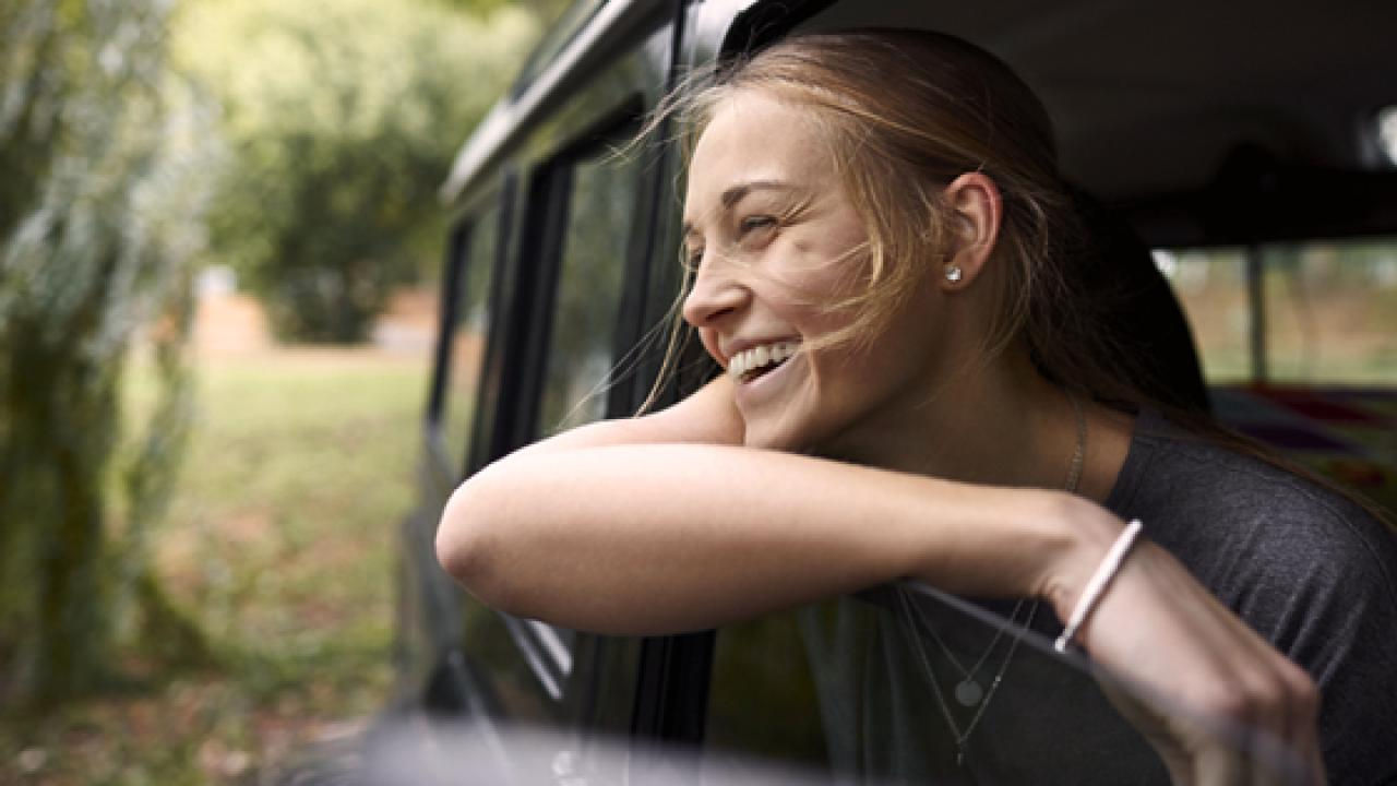 Girl with her head out the car window smiling