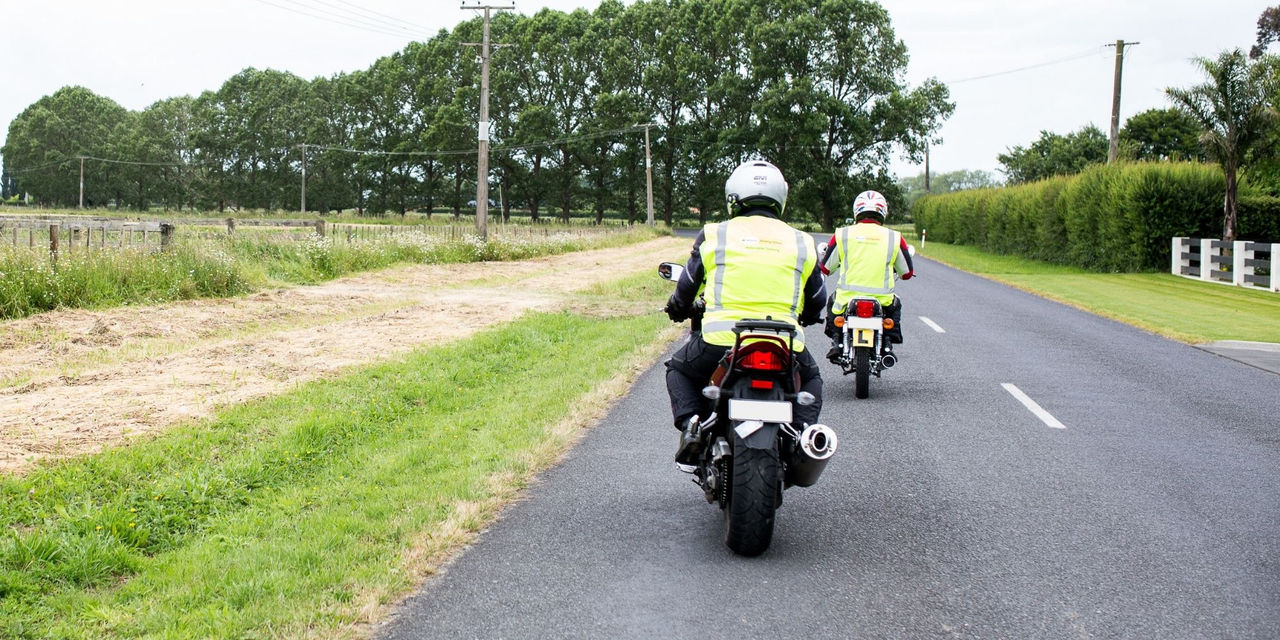 Two men riding motorcycle on a road