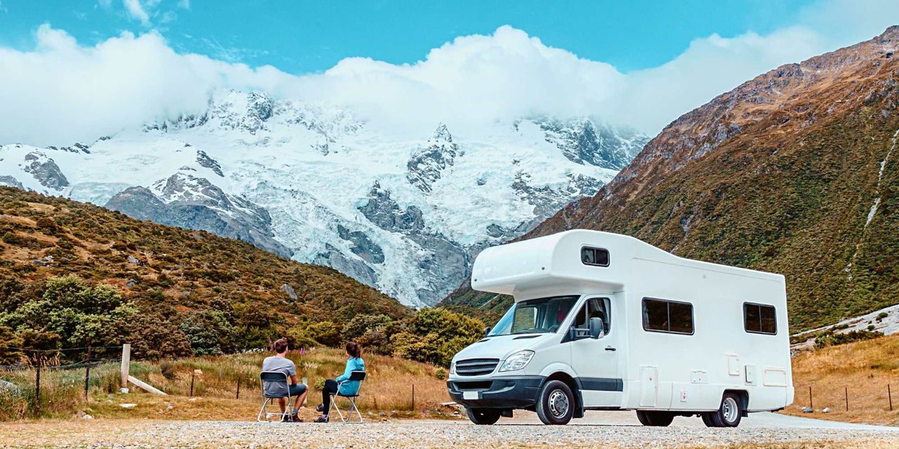 Couple sitting next to their campervan looking at the mountain view in winter