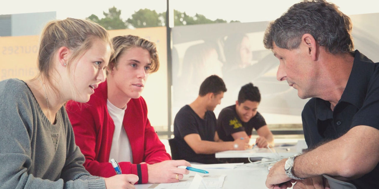 Two student drivers talking to a AA Defensive Driving Tutor