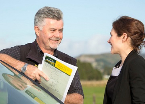 A driver instructor standing next to a woman 