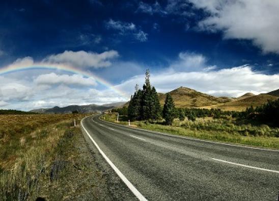 Country road view with a rainbow in the sky