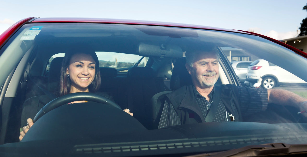 Driver and passenger smiling in car