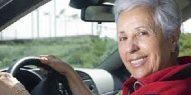 Elderly woman smiling in car driver's seat