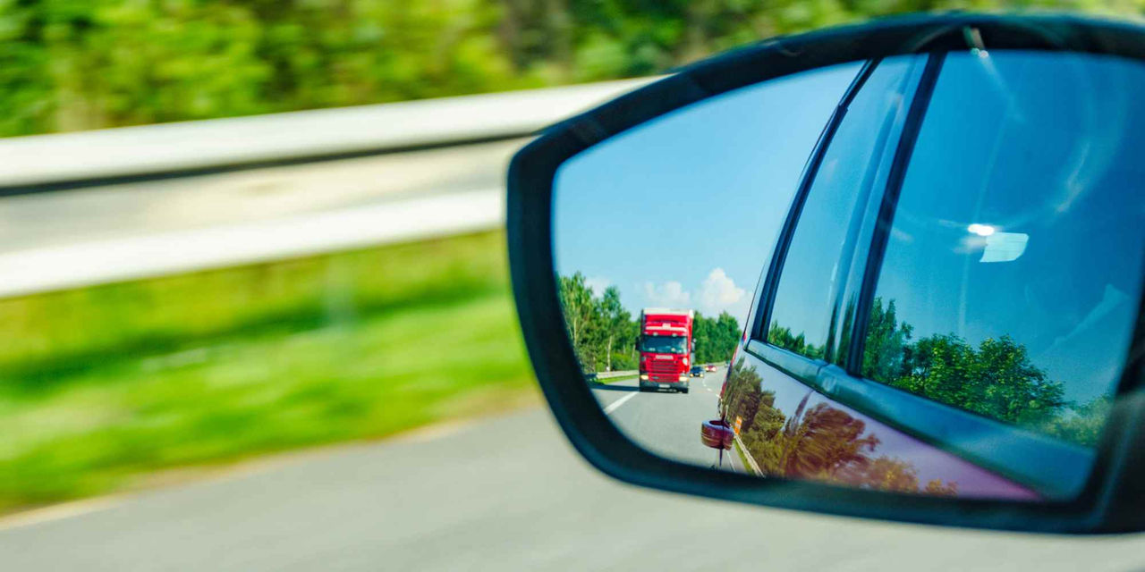 Side mirror showing truck behind the car