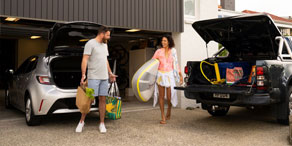 A couple taking groceries out of an open car trunk