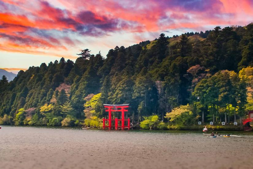 View of a lake and forest with red temple arches on the shore