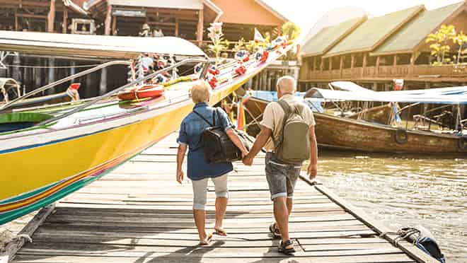Old couple walking on a pier holding hands