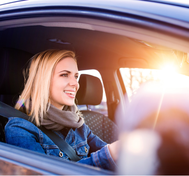Young woman sitting in the drivers seat of a car.