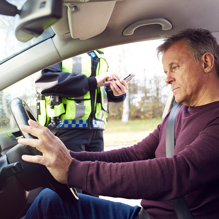 Man in the driver's seat with a sad expression as a police officer has pulled him over for a roadside breath test.