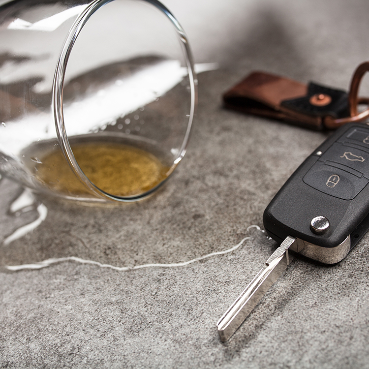 A beer glass spilling liquid next to a pair of car keys
