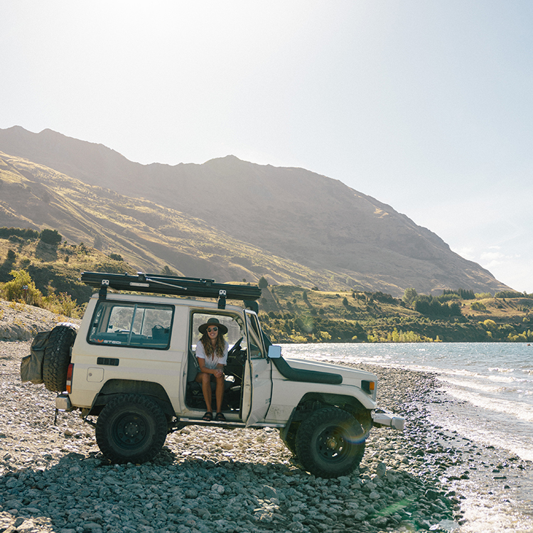 Woman sitting in truck on the beach
