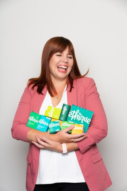 Portrait of Brianne West, creator of Ethique holding Ethique products