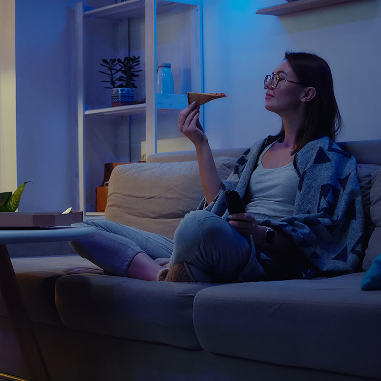 Woman eating pizza while watching a movie